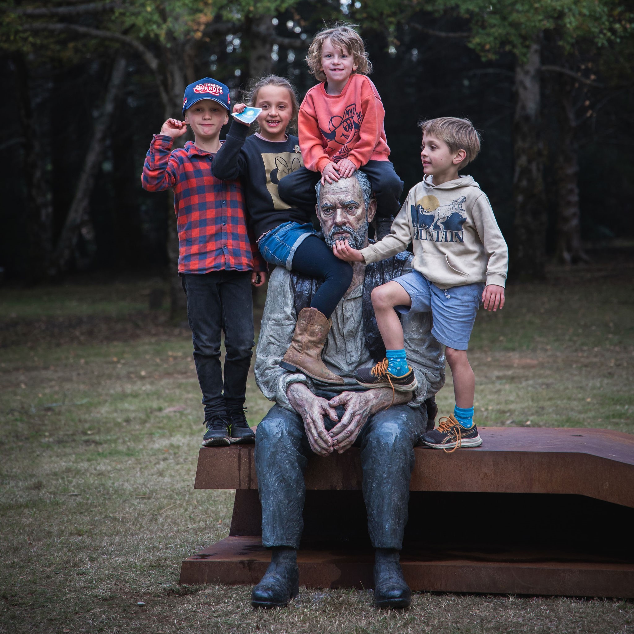 Children sitting of sculpture of man