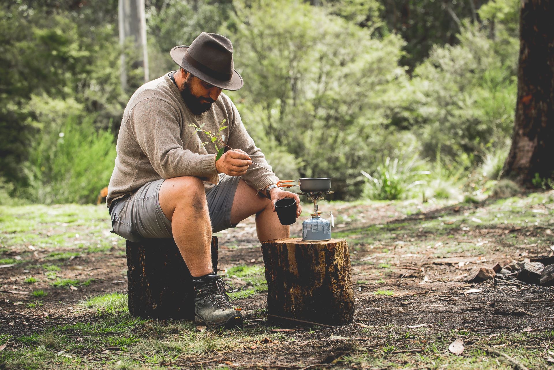 Camper sitting in forest using a gas burner